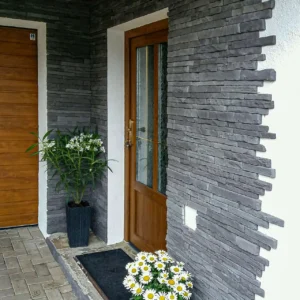 stěna domu s vchodovými dveřmi obložená lamaným kamenem